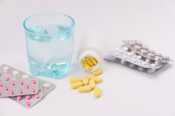  colorful pills , blister pack and glass of water on white background 