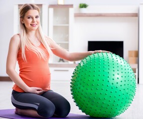 Fototapeta premium Young woman preparing for birth exercising at home