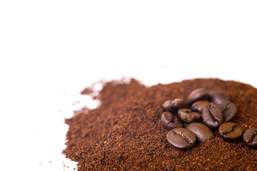 Roasted coffee beans at the top of a pile of ground coffee on an isolated white background. With white area for copy space text.