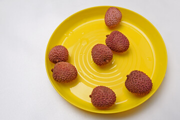 Lychee fruit on a yellow plate on a white background close-up
