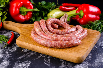 Fresh raw sausage on wooden board, Raw barbecue sausages with spices and vegetables. Top view Freshly made raw breed butchers sausages. Free space
