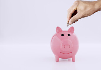 Men hand putting coin to a piggy bank on white background, Saving money concept
