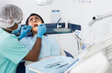 Fototapeta na wymiar Dentist checking teeth of patient woman sitting in medical center