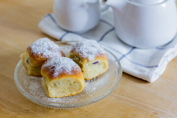 Sweet rolls 'Austrian buchteln' or Czech as well as  Slovakian 'Buchty' sprinkled with sugar on wooden table with tea