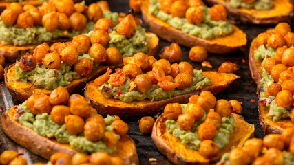 Sweet potato toast loaded with avocado guacamole and baked chickpeas on rustic metal oven-tray