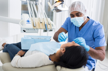 Dentist checking teeth of patient woman sitting in medical center