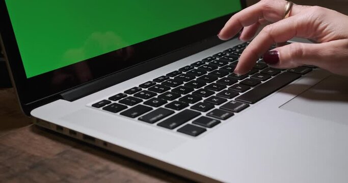 Woman Hand Typing on Laptop. Green Screen on Background