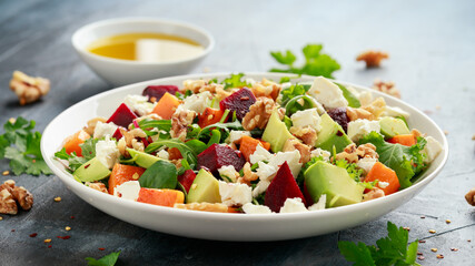 Healthy Butternut squash salad with beetroot, avocado, walnut and feta cheese in white bowl