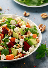 Healthy Butternut squash salad with beetroot, avocado, walnut and feta cheese in white bowl