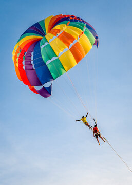 Flying a parachutist with an instructor on a colored parachute on a blue sky background