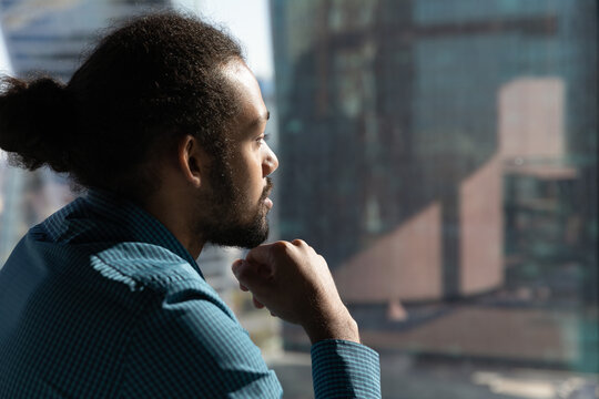 Close up of pensive African American man look in window distance thinking or pondering of future career opportunities. Thoughtful ethnic male make decision or plan. Business vision concept.