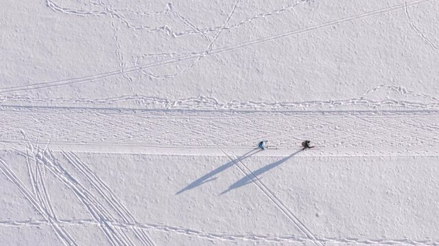 Skking from above - top shot of a drone looking down at a skiing couple at a beautiful winter day at a snow track