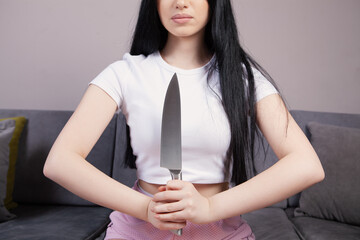 girl holding a large kitchen knife to protect herself