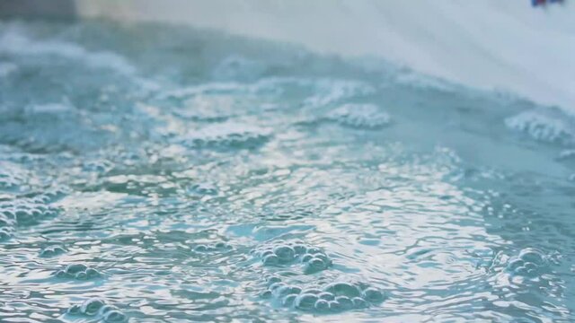 girl dipping hand in bubbling jacuzzi water