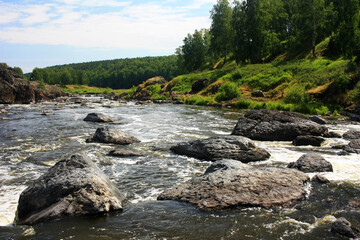 Fototapeta na wymiar A fast mountain river flows between green banks