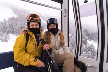 Two young blonde girls on a gondola of a ski resort in winter © martinscphoto