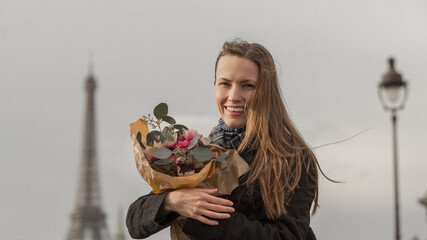 Beautiful woman with flowers in Paris over Eiifel tower, autumn or winter picture