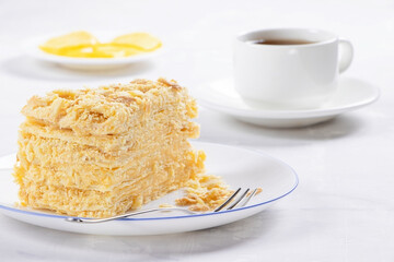 Napoleon Cake on a white plate and cup of tea. Traditional French dessert. Cake Napaleon of puff...