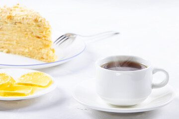 Napoleon Cake on a white plate and cup of tea. Traditional French dessert. Cake Napaleon of puff pastry on white background