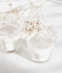 Fototapeta na wymiar Two white candles on a white surface for nordic and minimalism living 