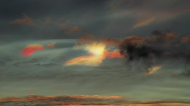 Bright glowing nacreous clouds behind dark clouds in the heavens
