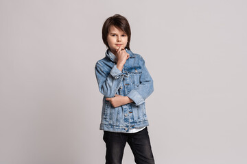 Handsome fashion little boy in jean jacket posing in studio. Model Test. Fashion and people concept