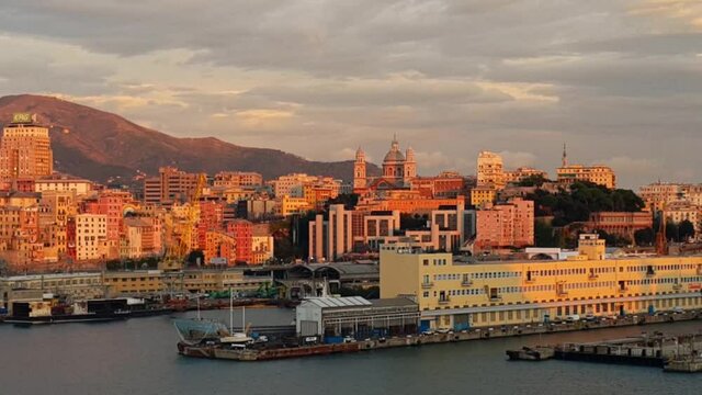 A fragment of the panorama of Genoa, which at sunset the sun painted in yellow-pink tones. View from the high side of the departing ship.