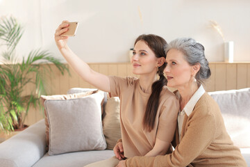 Obraz na płótnie Canvas Happy middle aged mother and daughter taking selfie at home.