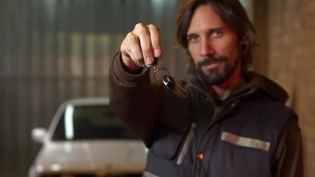 Mechanic man holds out car keys and jingles them in circles, Close Up