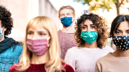 Urban crowd of citizens walking on city street covered by face mask - New normal society concept with young people on worried anxiety mood - Selective focus on bright contrast filter