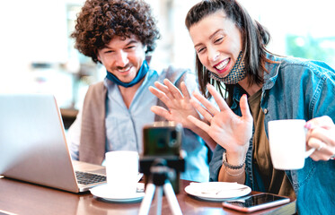 Young millenial couple sharing creative content with facemask - Digital marketing concept with next generation influencer having fun on video stream - Vlogging time at startup co working space