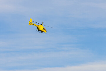 yellow helicopter flying against the blue sky