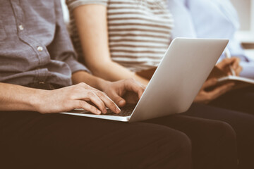 Fototapeta premium Group of casual dressed business people working at meeting or conference, close-up of hands. Businessman using laptop computer. Teamwork or coaching concept