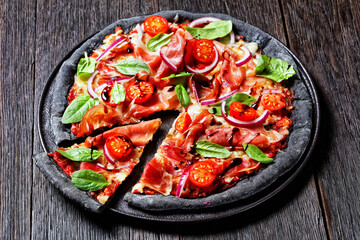 black dough pizza with jamon, top view