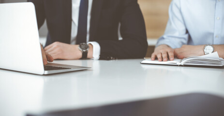 Unknown business people using laptop computer at the desk in modern office. Businessman or male entrepreneur is working with his colleague. Teamwork and partnership concept