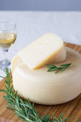 A head with a slice of classic Italian cheese Caciotta made from natural cow's milk on cutting board, selective focus