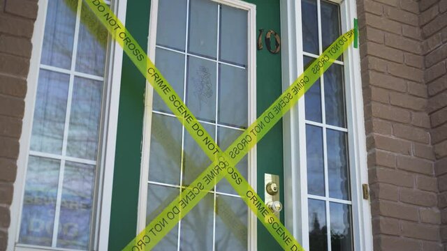 Yellow crime scene do not cross tape across front door of house