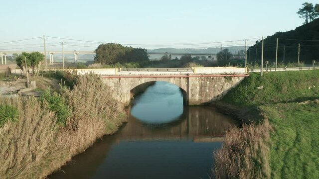 Flying Towards Old Stone Arch Bridge Over Tranquil Lake Of Alcobaca River Near Nazare, Portugal. - Drone Shot