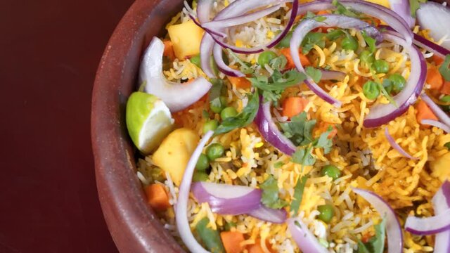 Fork dives into traditional Indian Hyderabadi dum biryani, close up slow motion slider 4K