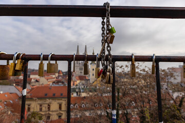 Fototapeta premium Zagreb, Croatia-December 13th, 2020: Viewpoint over Zagreb city rooftops with famous gothic cathedral in the background and hanged padlocks on iron fence with love messages