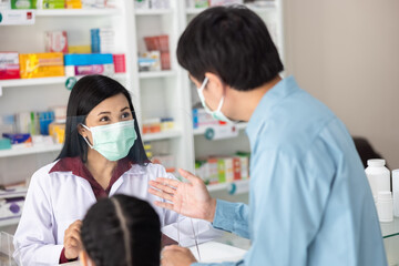asian professional young women pharmacist wearing face mask while pescribing medicine to customer...