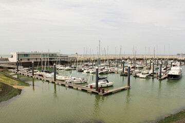the new marina with yachts and fishing boats in turquoise water in front of a michelin starred restaurant in cadzand, the netherlands
