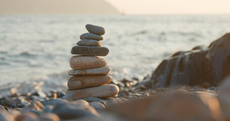Balanced pebble pyramid on the beach at sunset