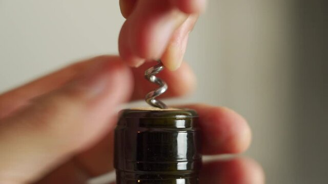 Extreme close up of a bottle of red wine being opened with a corkscrew