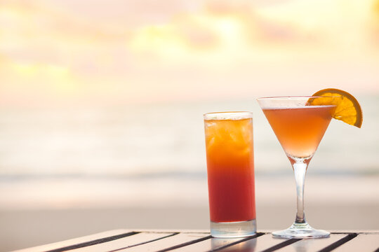 margarita cocktail and aperol spritz on table by the beach. sunset background