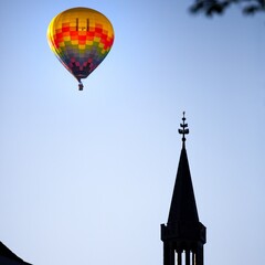 Fototapeta na wymiar colorful hot air balloon floating over cathedral rooftop