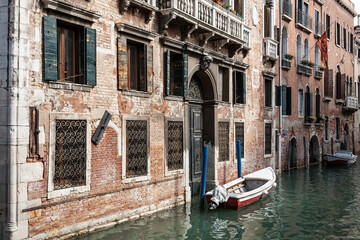 Fototapeta na wymiar Typical venetian canal with a boat outside an old palazzo building, Venice, Italy