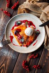 Pancakes with ice cream and berries on a wooden background.