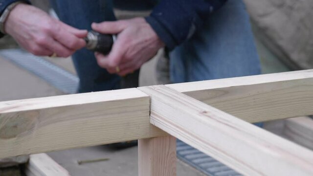 A man swaps drill bits and countersinks some wood.