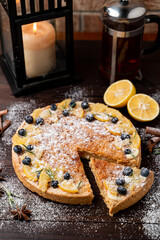 Lemon tart as a christmas treat in festive atmosphere with candles and snow around
